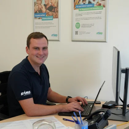 Florian Gottschalk sitzt an einem Rechner und lacht in die Kamera